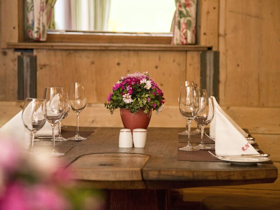 Ein Holztisch gedeckt mit Weingläsern, Tellern und einer floralen Tischdekoration.