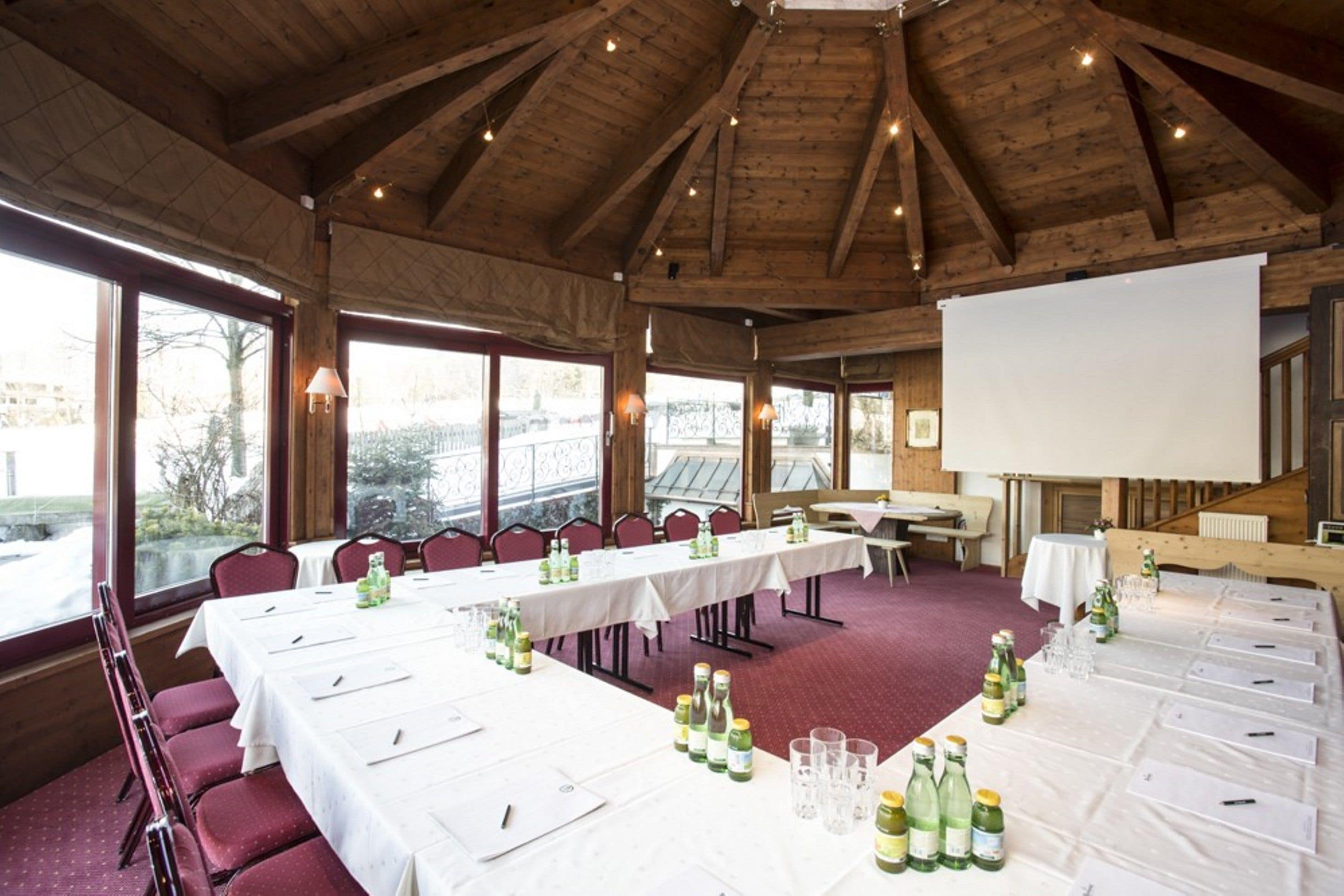 A conference room with long tables, chairs, and a projector screen.
