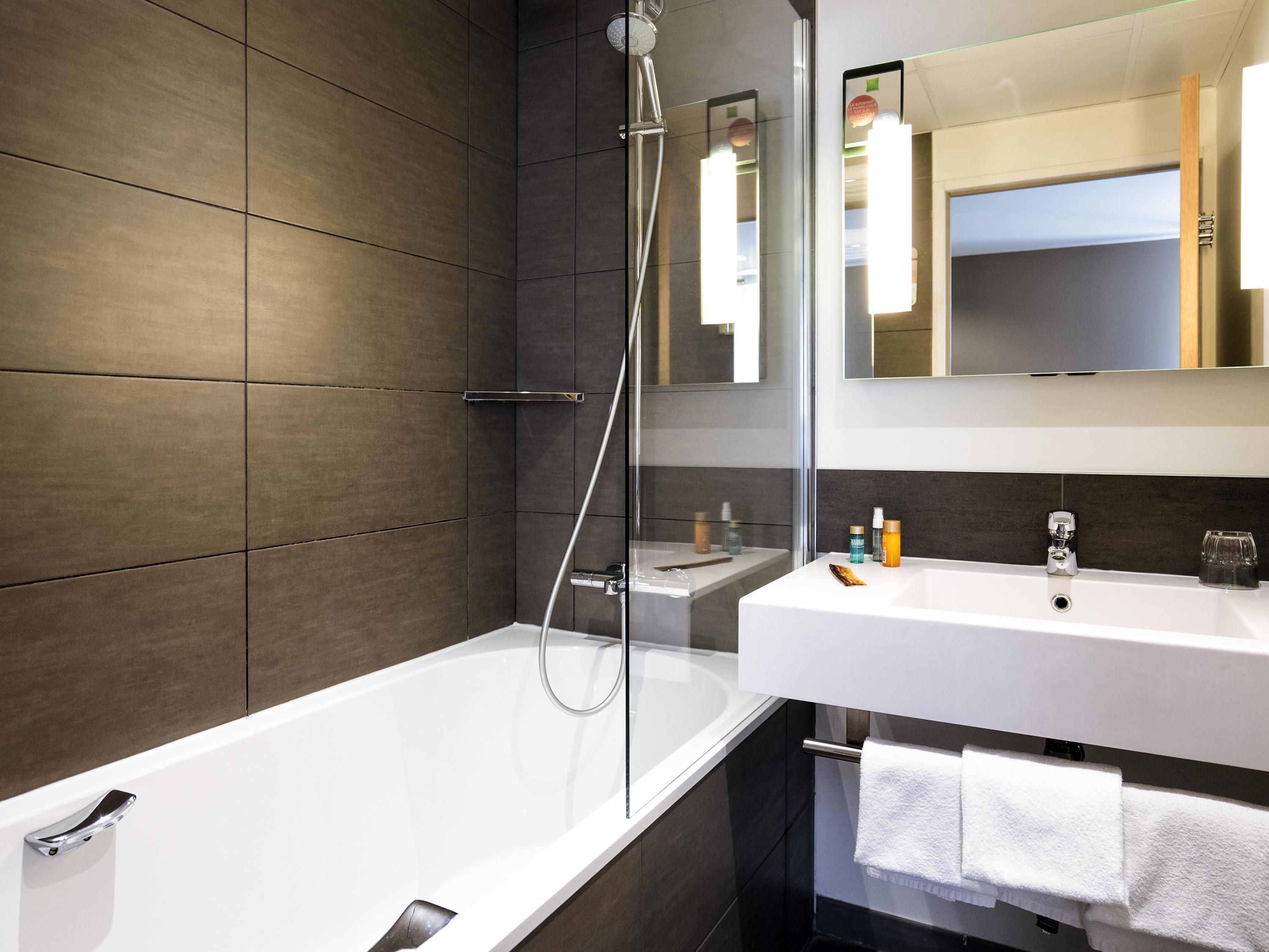 Un baño moderno con bañera, ducha y tocador con espejo.