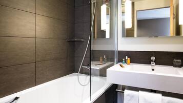 Un baño moderno con bañera, ducha y tocador con espejo.
