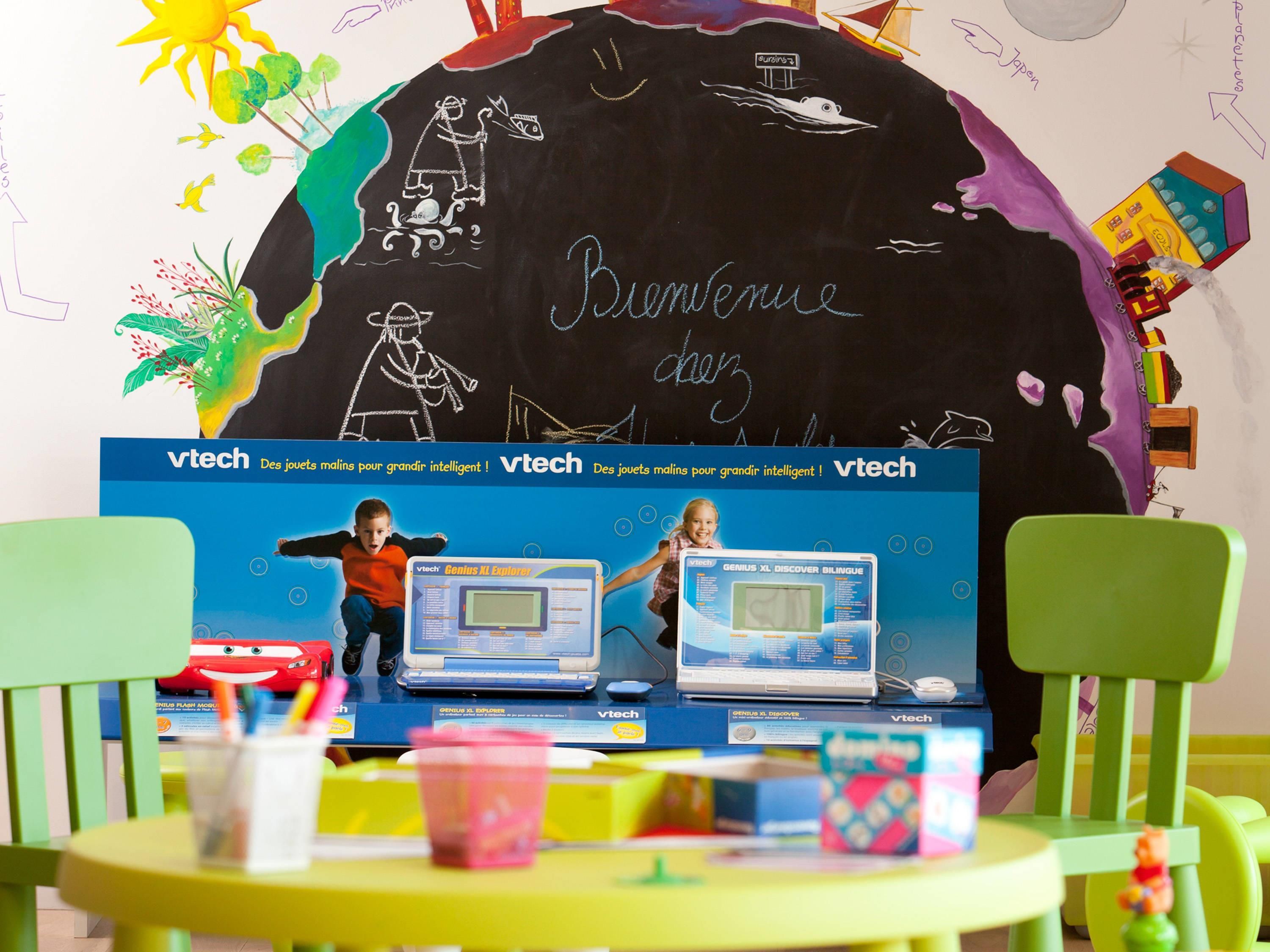 A classroom with educational posters, a chalkboard, and two children playing with educational toys.