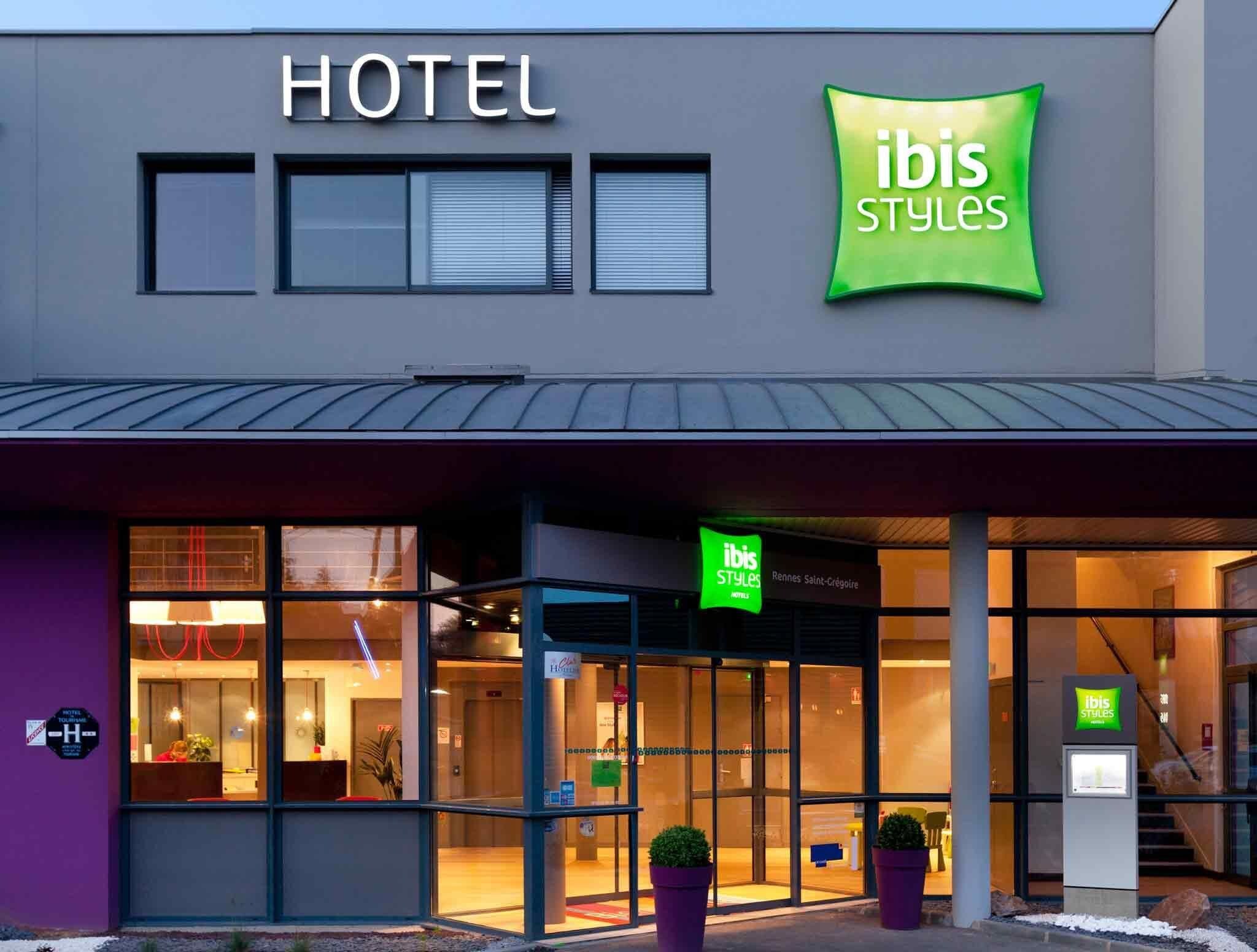 Un hotel con fachada moderna, que destaca un cartel prominente con la palabra "HOTEL" y la marca "ibis Styles".