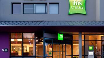 Un hotel con fachada moderna, que destaca un cartel prominente con la palabra "HOTEL" y la marca "ibis Styles".