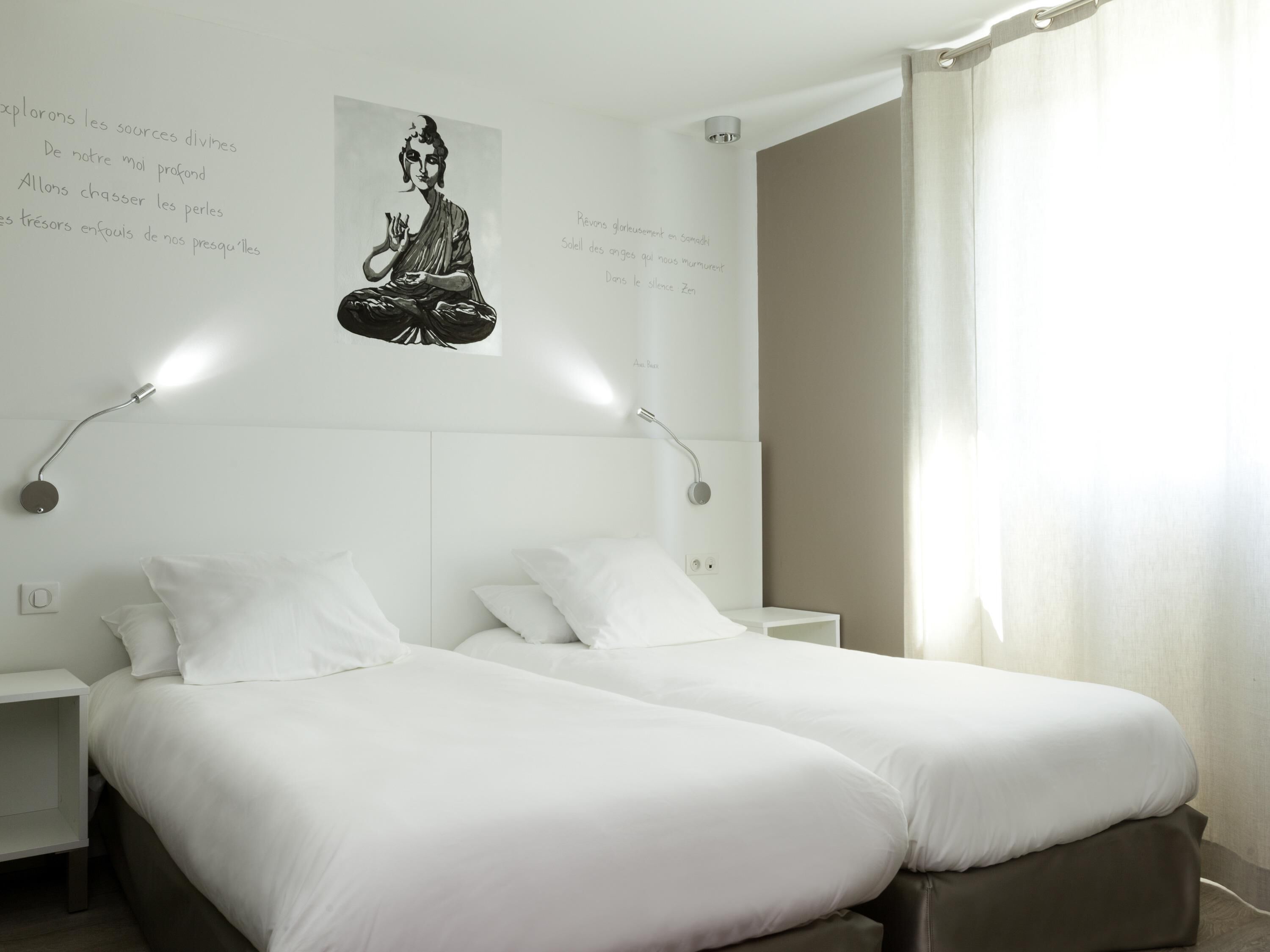 A hotel room with two beds, a wall-mounted light fixture, and a poster of a meditating figure.