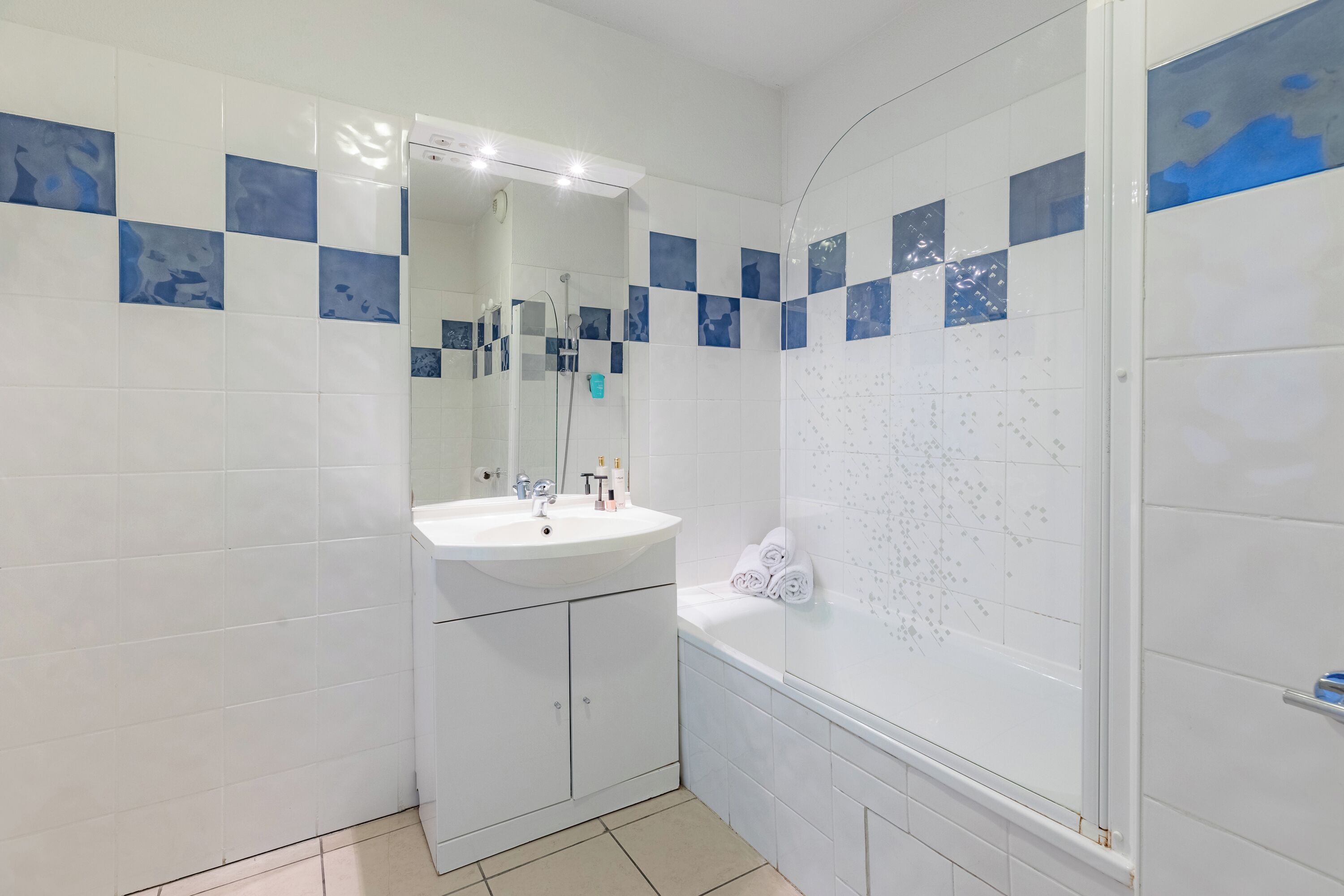 A bathroom with a sink, mirror, and bathtub.