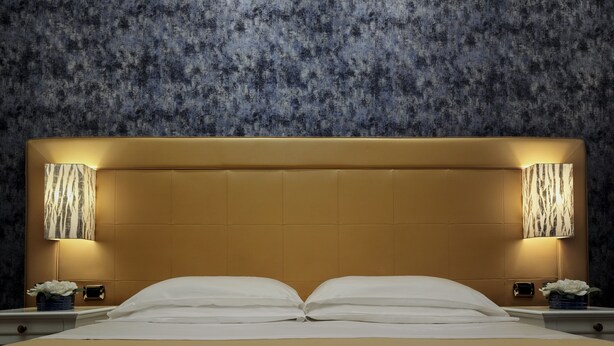 A hotel room with a large bed, two bedside lamps, and a textured wall. - Ca' Bragadin Carabba (Venice)