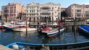 A canal with boats docked, surrounded by historic buildings with arched windows and balconies. - Ca' Bragadin Carabba (Venice)