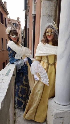 Due persone in costume storico che si trovano su una stretta via fiancheggiata da edifici.