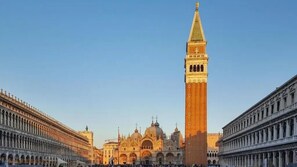 Una piazza storica con un'imponente torre dell'orologio, una cattedrale e architettura neoclassica.