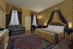 Una habitación de hotel con una cama grande, un sofá, una mesita y un armario.