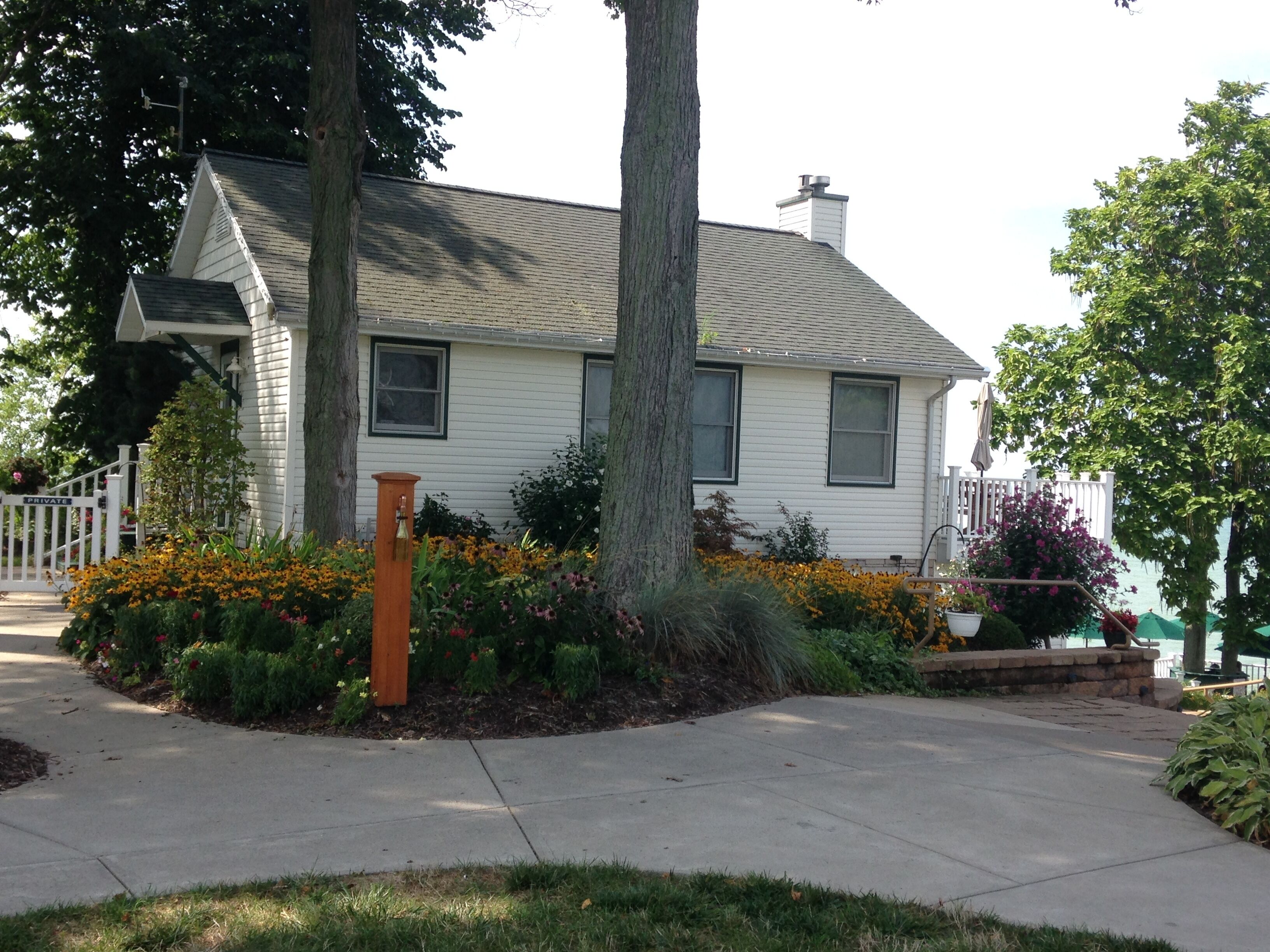 A two-story house with a front porch, a mailbox, and a well-maintained garden with various flowers.