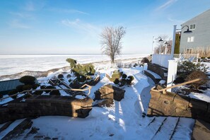 Une zone côtière avec un mur de pierre, une clôture blanche et un bâtiment doté d’un balcon.
