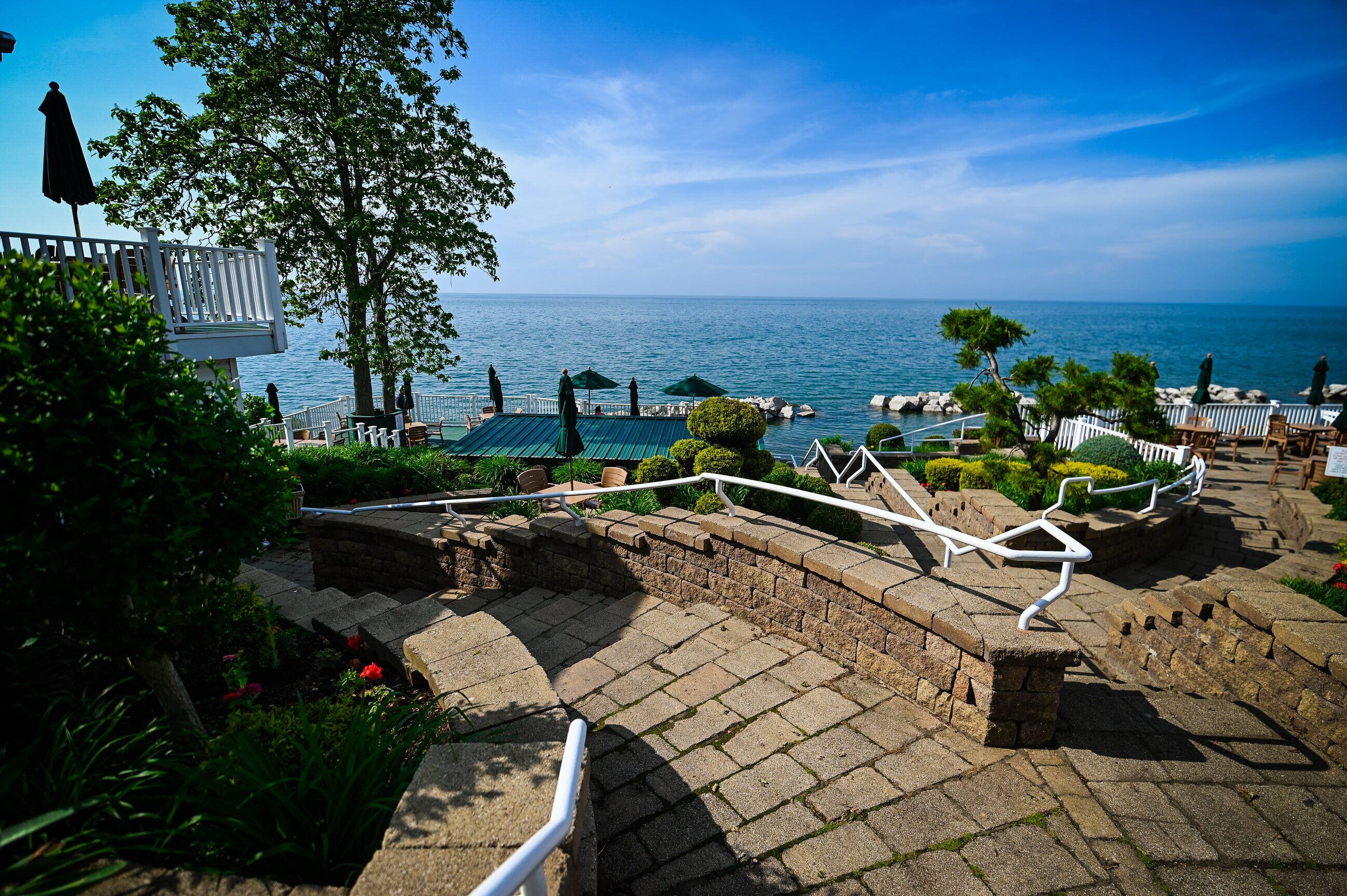 A stone pathway leading to a terrace with outdoor seating and a view of the sea.