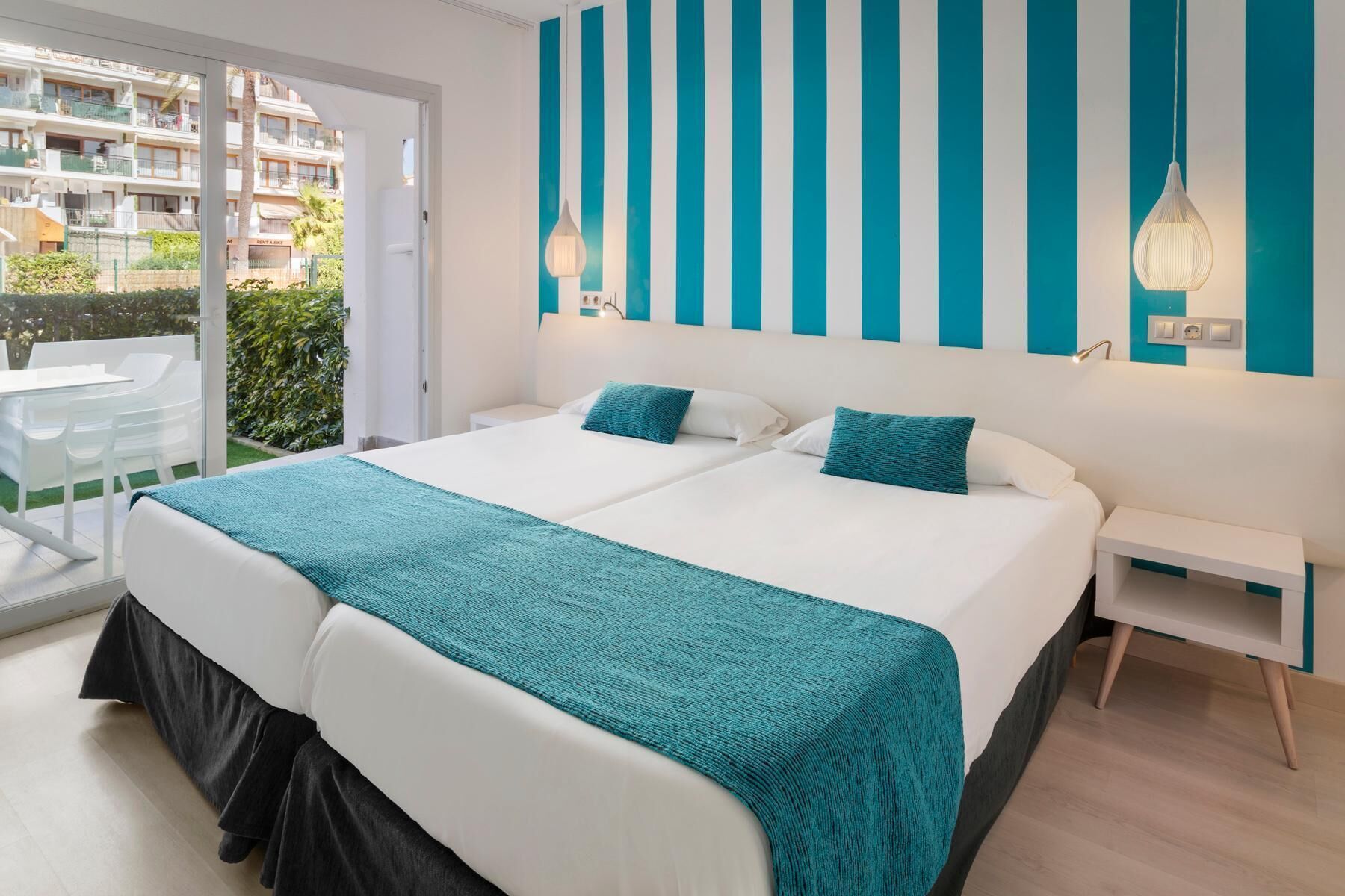 Ein Hotelzimmer mit einem großen Bett, einem kleinen Nachttisch und Blick auf den Balkon.