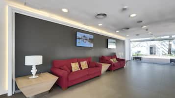 A reception area with a red sofa, a white lamp, and a digital screen displaying a winter scene.