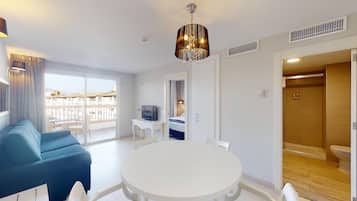 Een moderne hotelkamer met balkon, een ronde eettafel, een bank en een televisie.