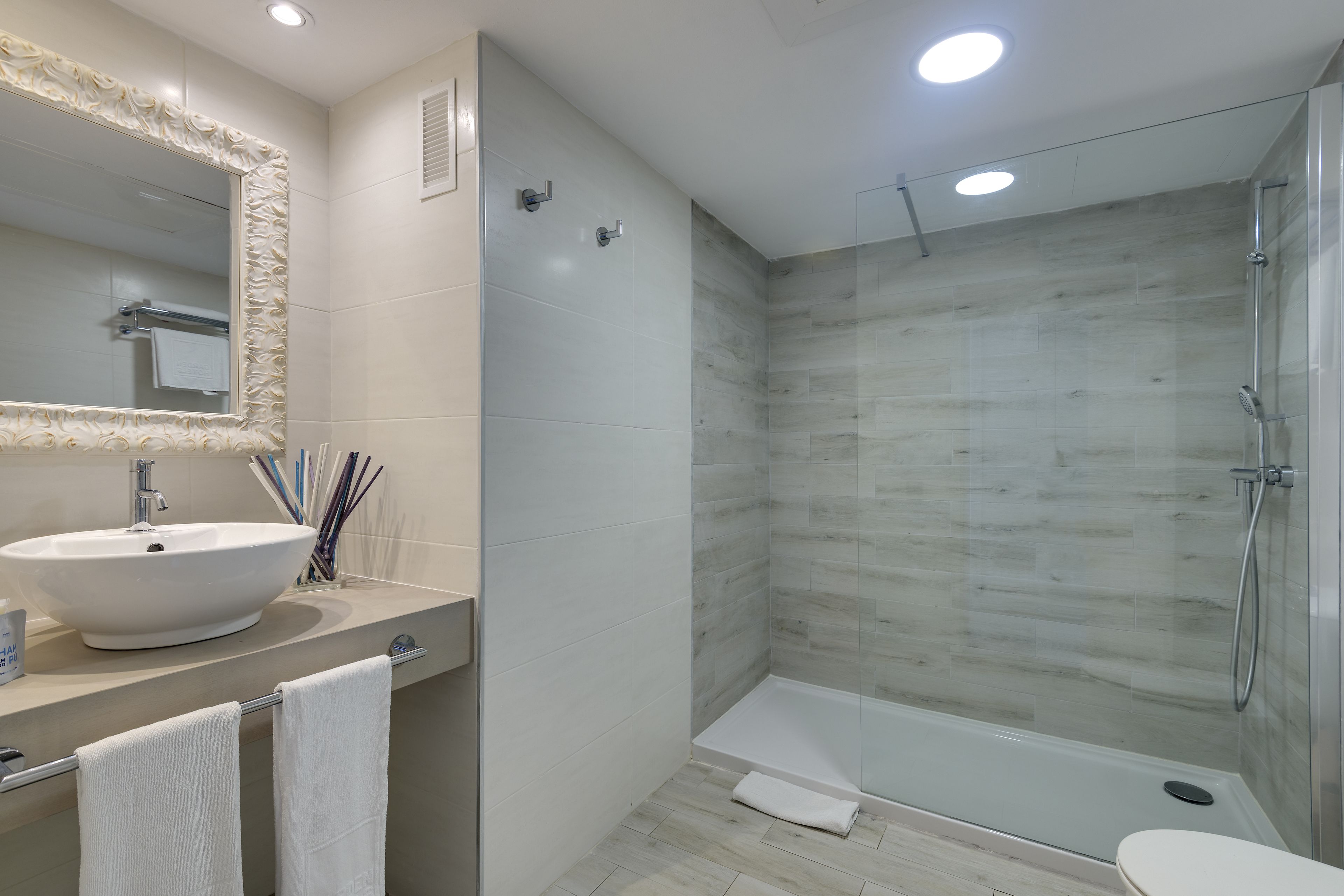 Un baño moderno con un lavamanos grande, espejo y ducha.