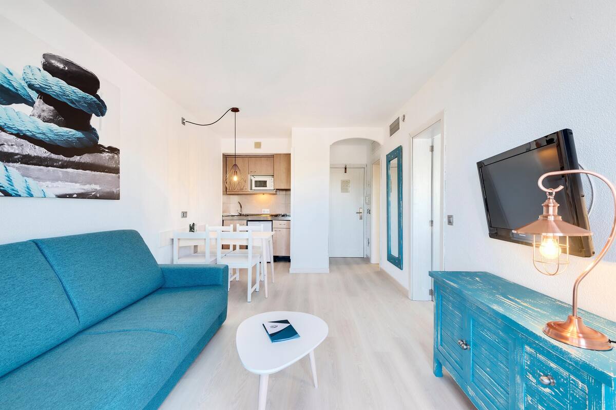 Een moderne woonkamer met een bank, een salontafel, een blauwe kast en een televisie.