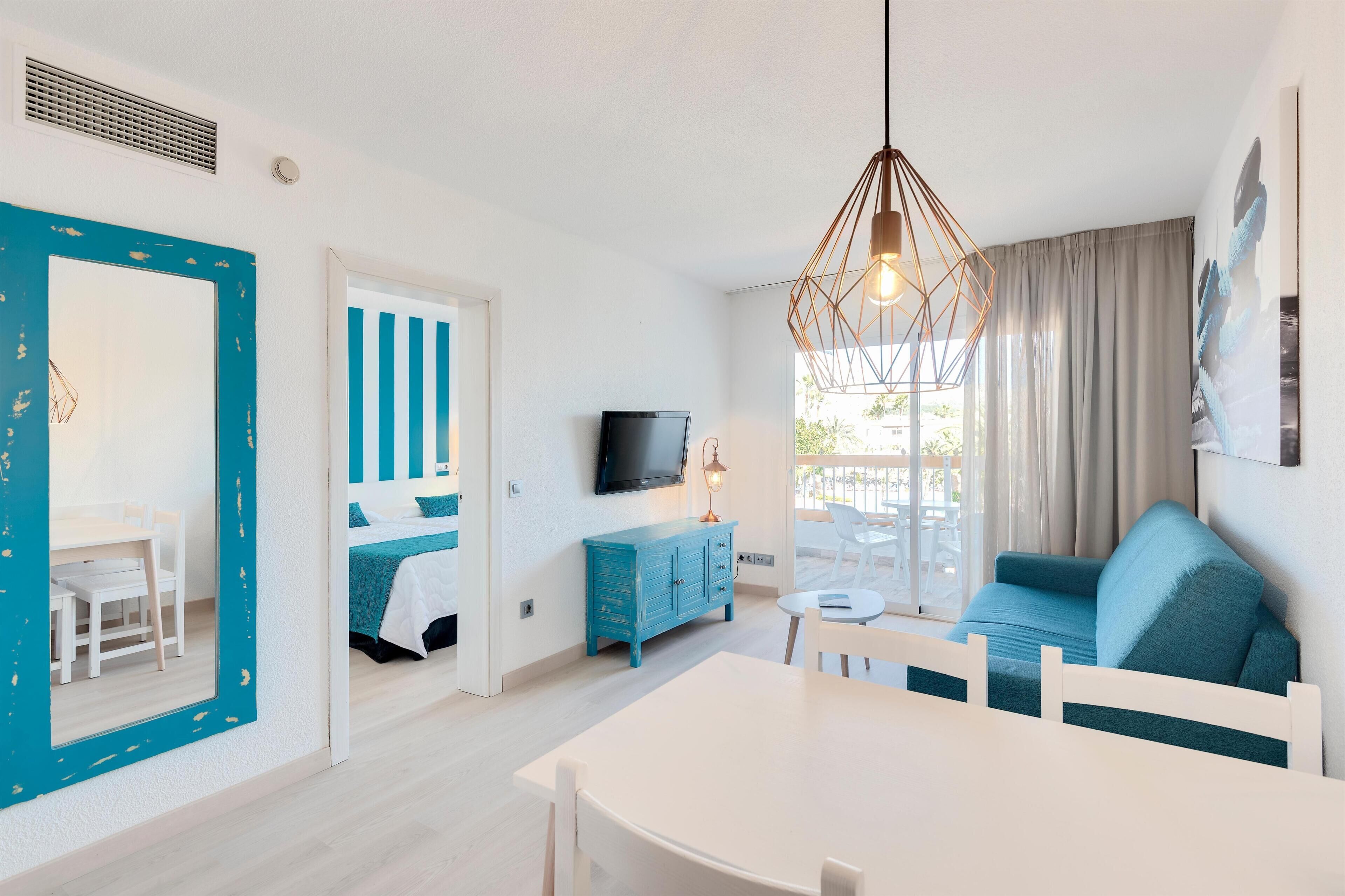 Una sala de estar moderna con comedor, televisor y sofá azul.