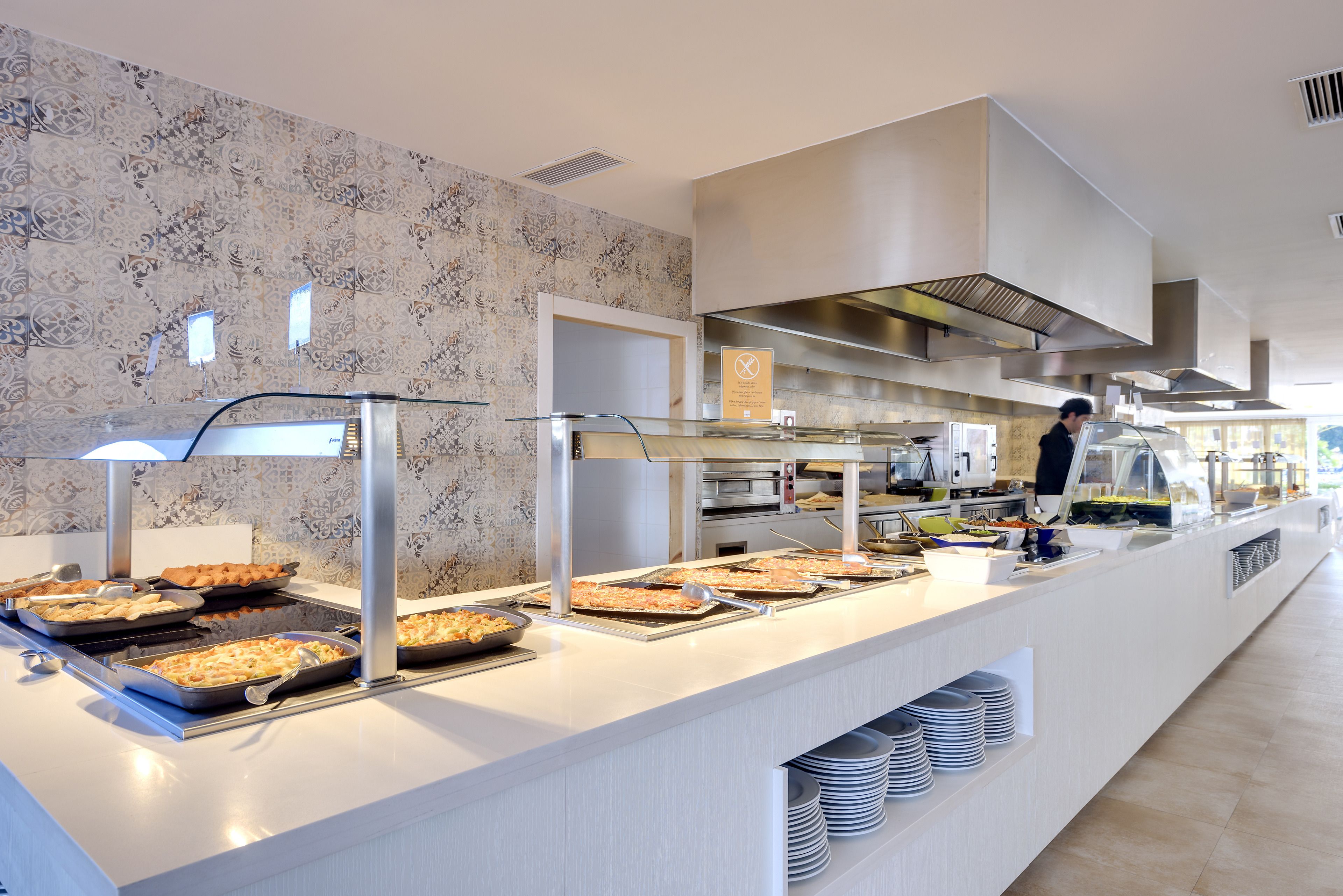 Disposición de buffet con diferentes alimentos y una persona sirviendo.