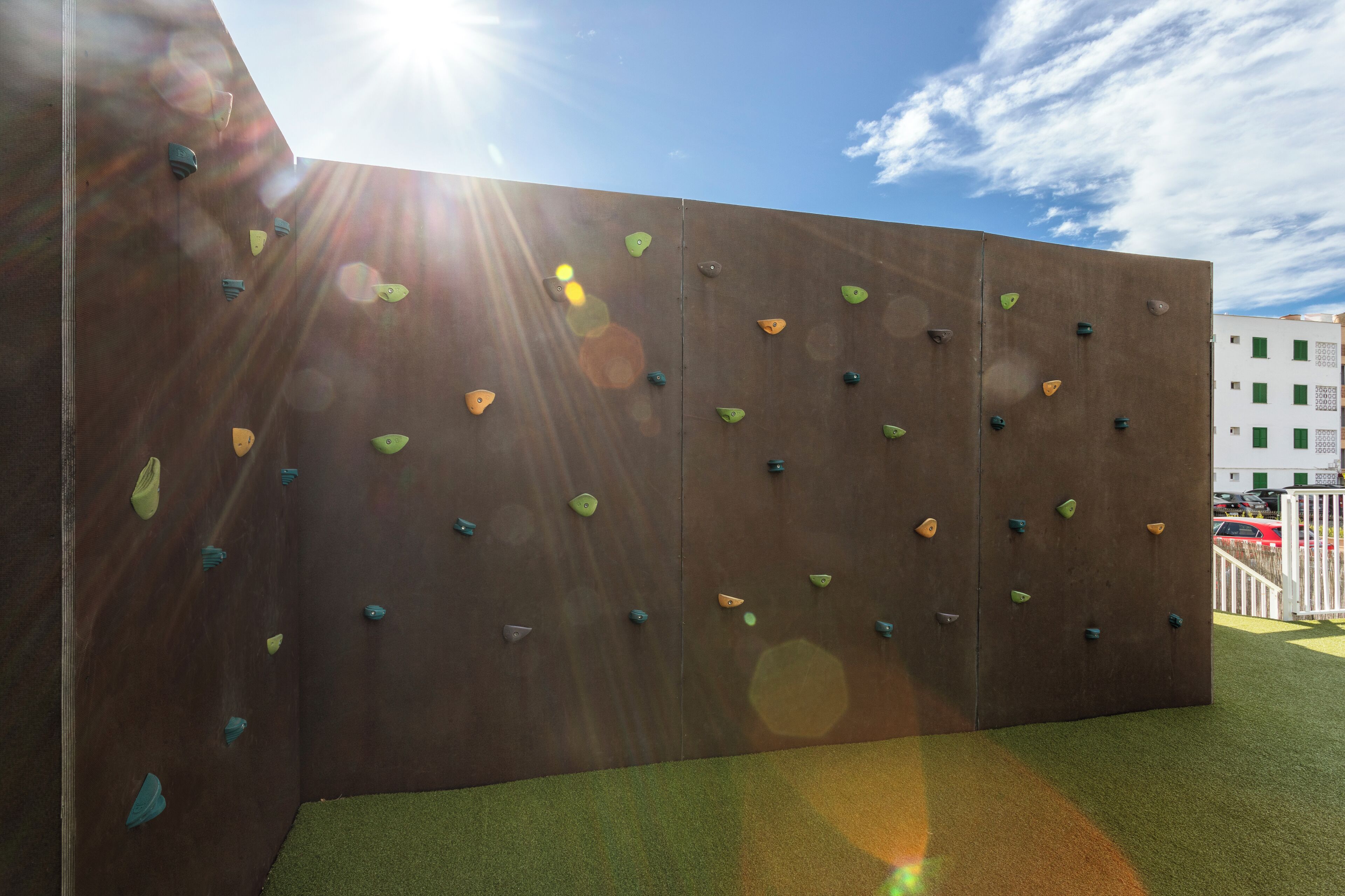 A climbing wall with various holds and a clear sky.