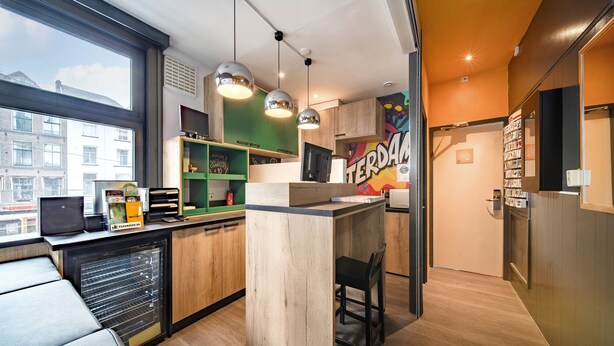 A modern kitchen with a built-in island, pendant lighting, and a view of the city. - Princess Hostel Amsterdam (Amsterdam)