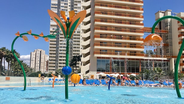Una piscina con fuentes y sillas de descanso.