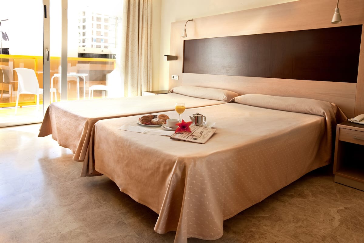 A hotel room with two beds, a breakfast tray, and a city view.