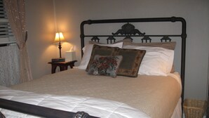 Un lit bien fait, avec une tête de lit en bois, une lampe de chevet et un coussin décoratif.