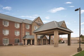 A Country Inn & Suites building with a brick facade, multiple windows, and a covered entrance area.
