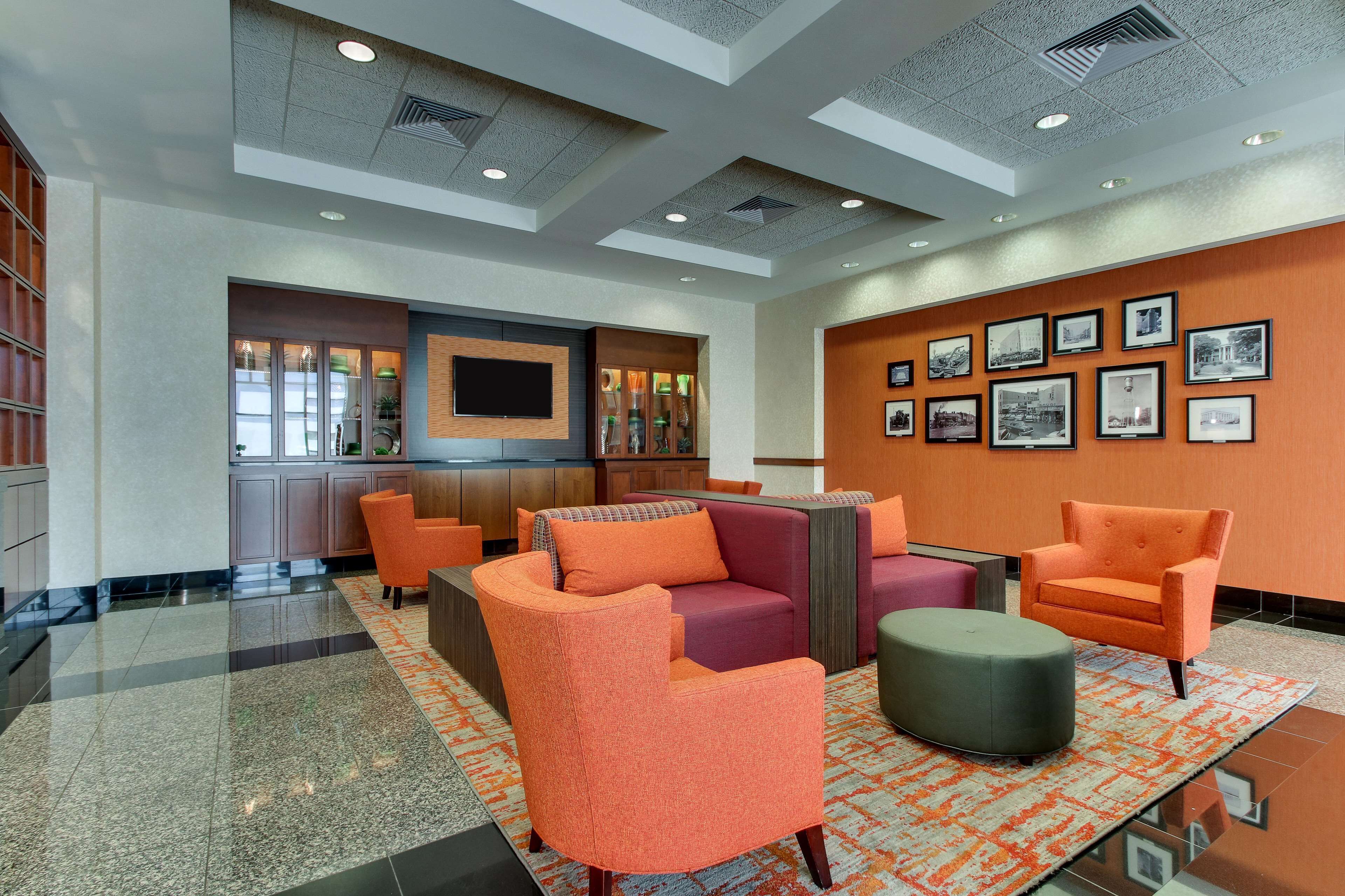 A lobby with orange and purple seating, a TV, and framed pictures on the wall.