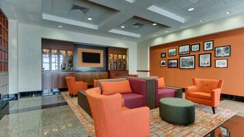 A lobby with orange and purple seating, a TV, and framed pictures on the wall.