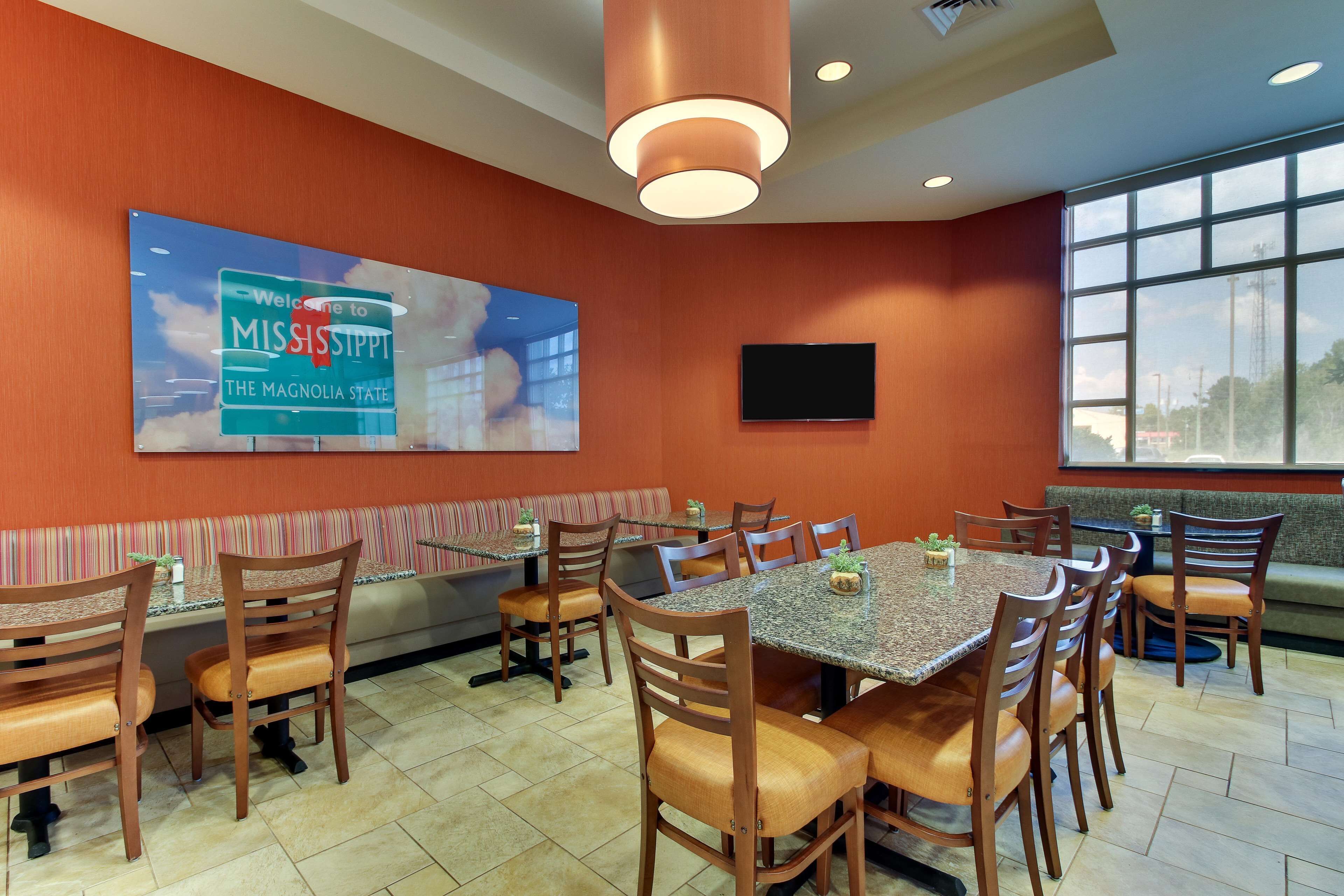 A conference room with a large table, chairs, a television, and a wall sign.