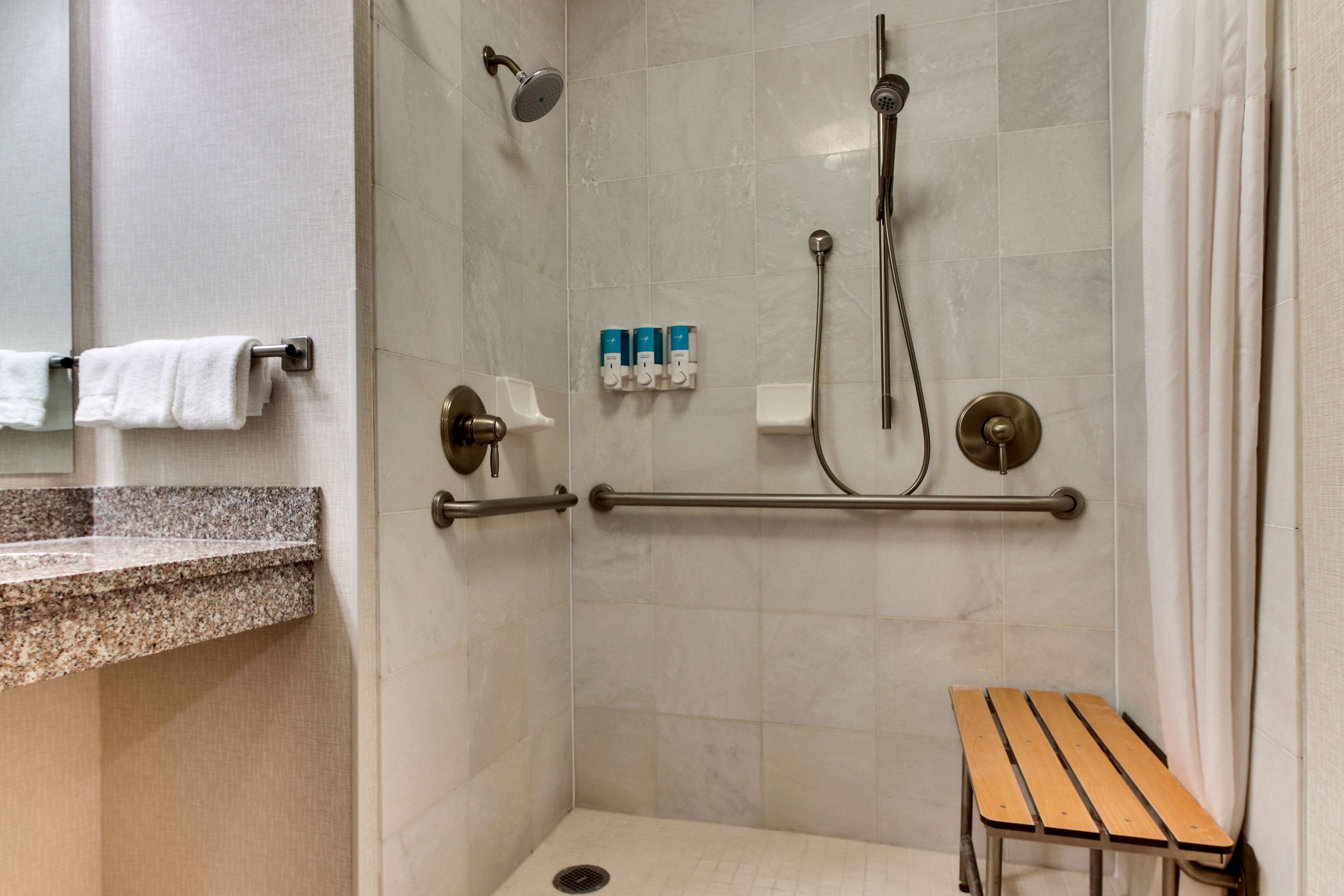 A shower area with a grab bar, a bench, and a towel rack.
