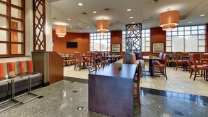 A spacious restaurant with high ceilings, multiple dining tables, and chairs. There are large windows providing natural light and a seating area with a sofa and a small table. - Drury Inn & Suites Meridian (Meridian)