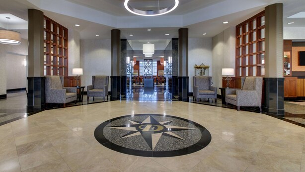 A spacious lobby with a central floor design, seating arrangements, and a view into the dining area. - Drury Inn & Suites Meridian (Meridian)