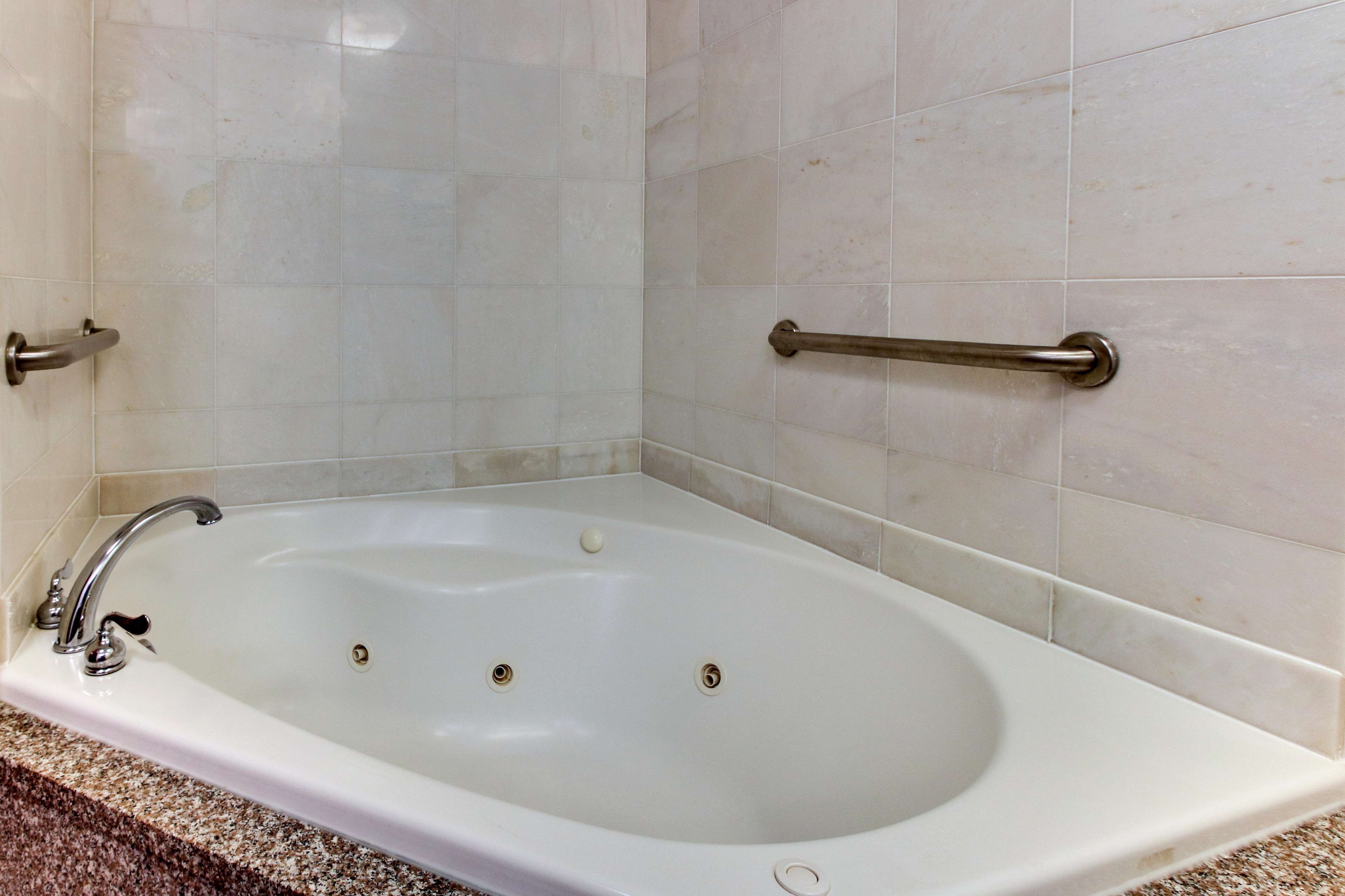Una bañera blanca con dos llaves y un asidero en el lado derecho.