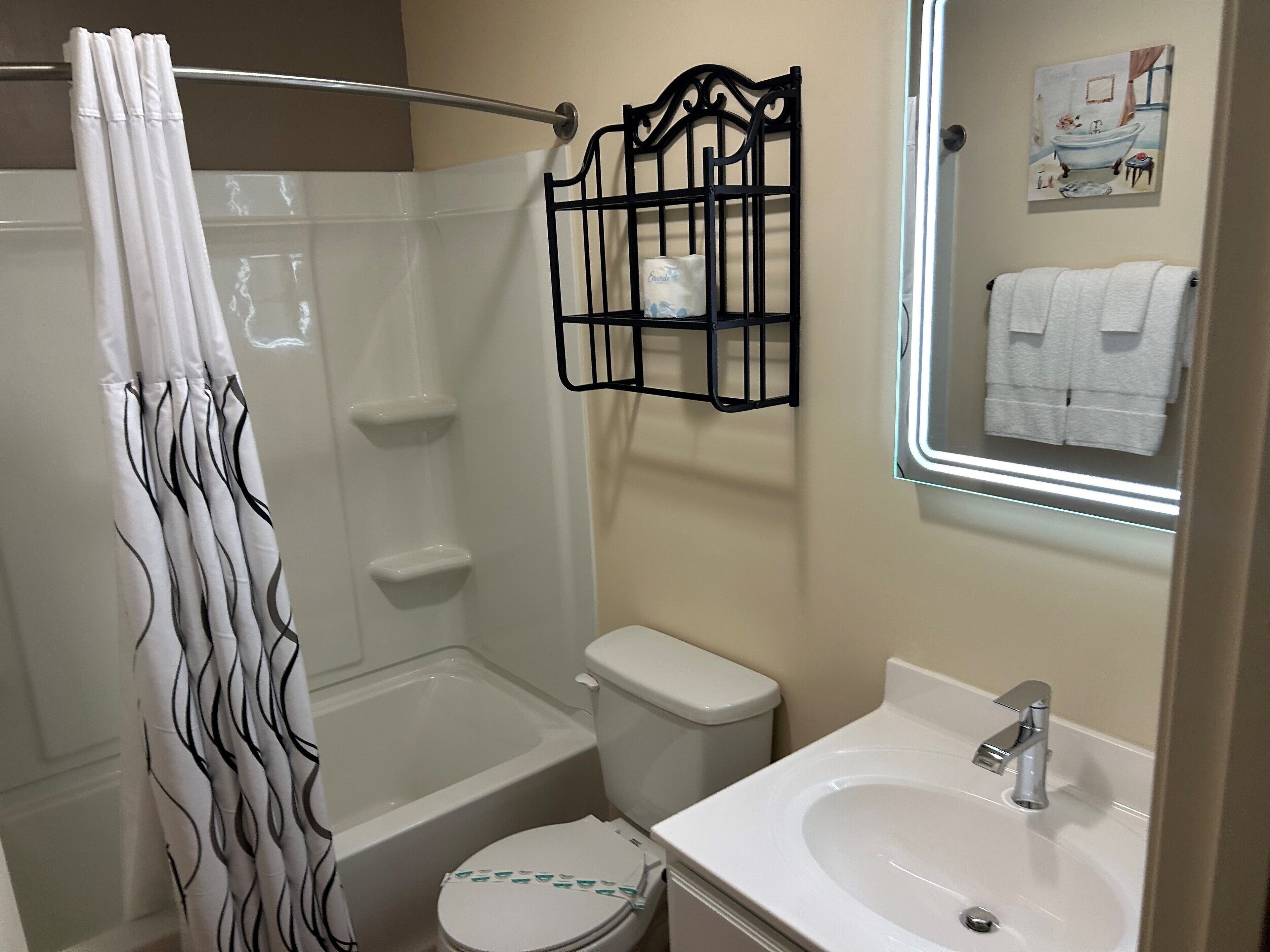 Ein Badezimmer mit Dusche, Toilette, Waschbecken und Handtuchhalter.