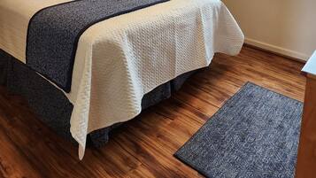 A neatly arranged bedroom with a bed, bedside table, lamp, and a decorative wall piece.