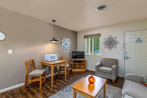 Ein kompakter Wohnraum mit Esstisch, Stühlen, einer Couch, einem Fernseher und einer Wanddekoration.
