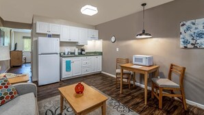 Une cuisine moderne avec des meubles blancs, un four à micro-ondes et un coin repas comprenant une table et des chaises en bois.