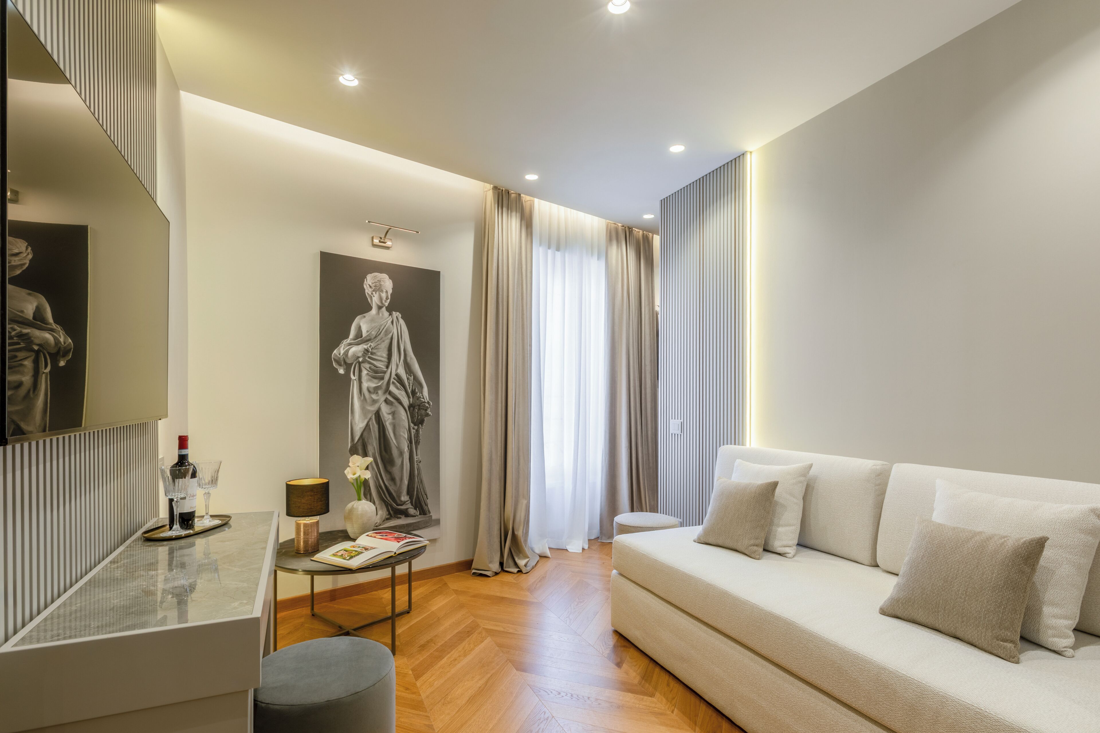 A modern living room with a sofa, a coffee table, a statue, and a window with curtains.