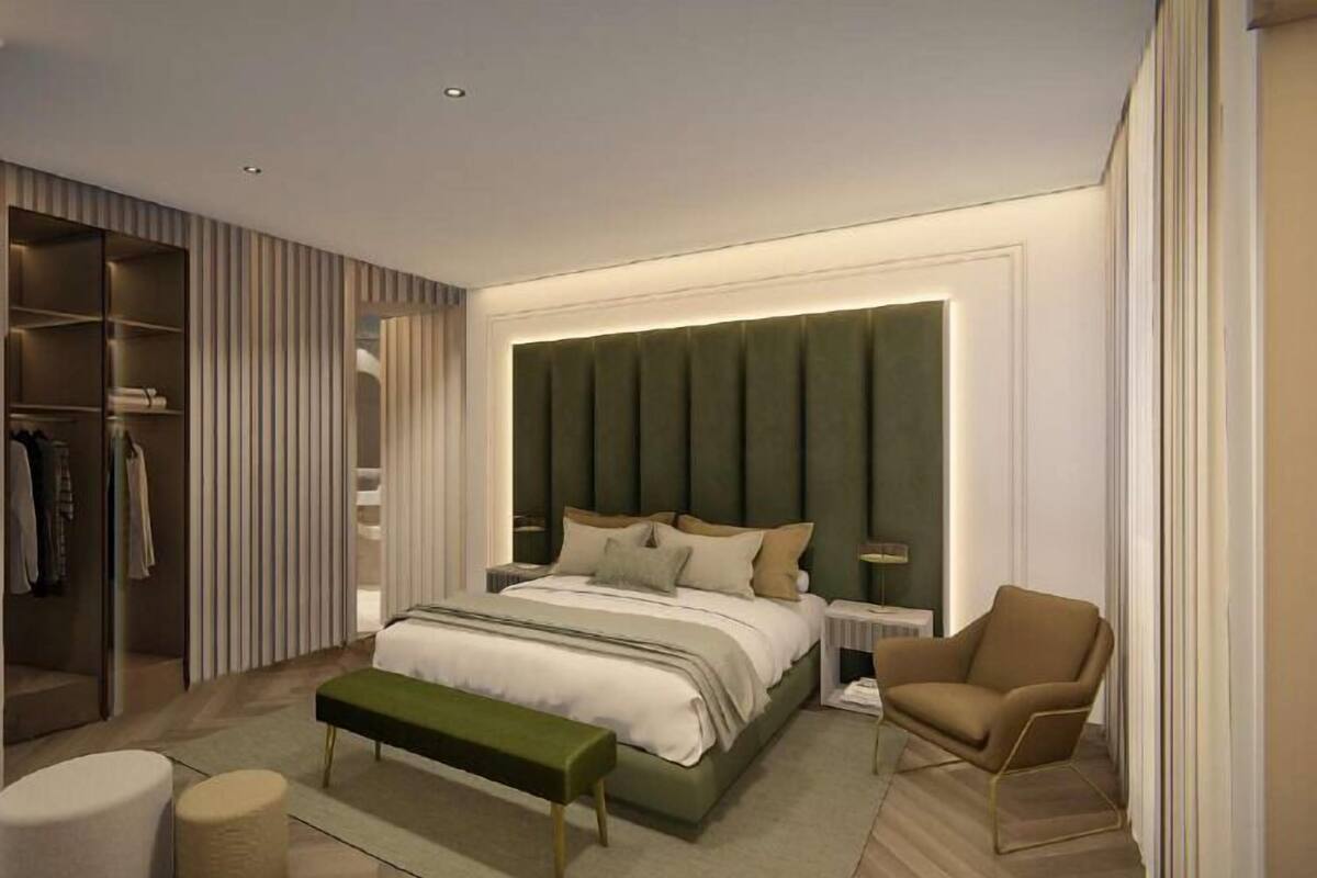 A modern bedroom with a large bed, a bench, a chair, a wardrobe, and a bedside table.