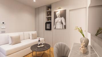 Una sala de estar moderna con un sofá blanco, una mesa de centro redonda, una mesita auxiliar de mármol y una estatua.