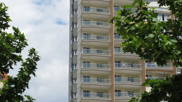 A high-rise building with multiple balconies and a clear sky.