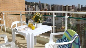 A balcony with a table, chairs, and a flower arrangement.