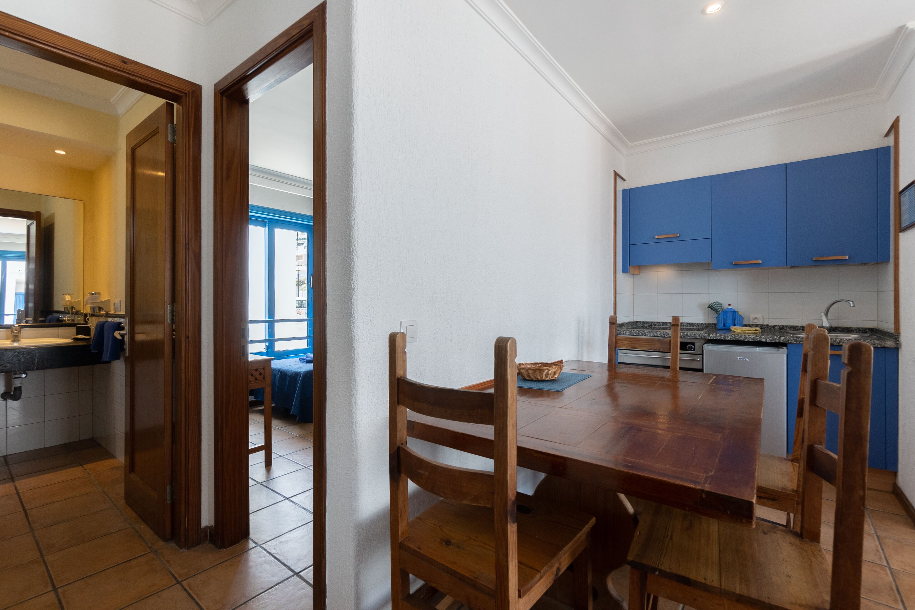 A modern kitchen with blue cabinets, a wooden dining table, and a kitchen island.