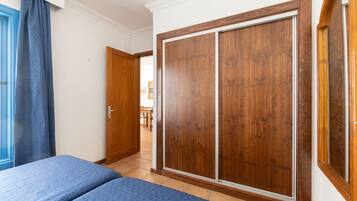 A bedroom with a bed, a wardrobe, and a door leading to another room.