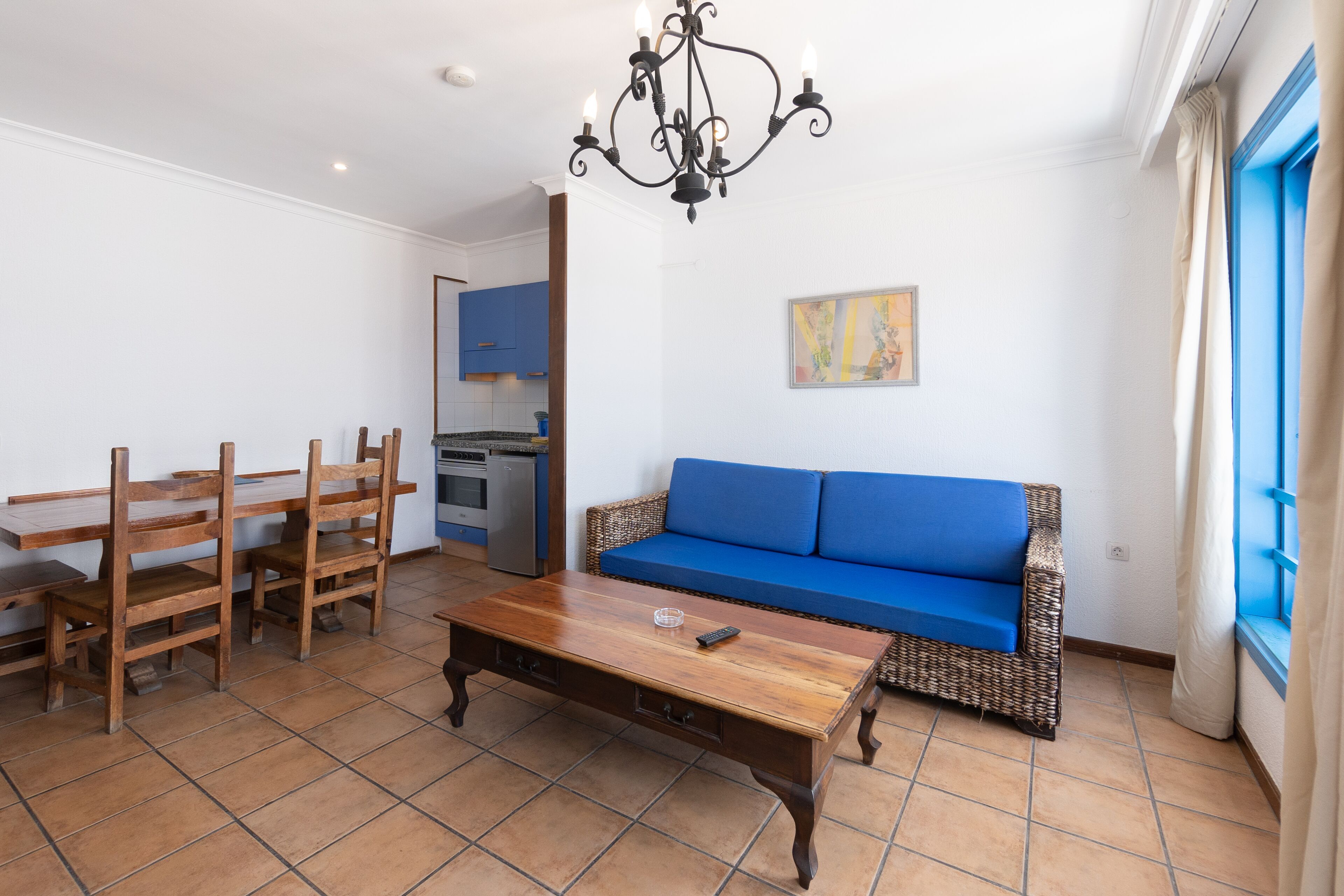 Ein Wohnzimmer mit Couch in Blau, Holztisch und Holzstühlen.