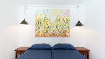 A bedroom with a bed, two bedside tables, and a colorful abstract painting on the wall.